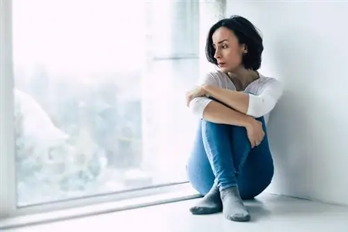 Женщина сидит у стены