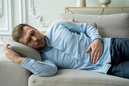 Боль в поджелудочной железе - мужчина держится за живот.