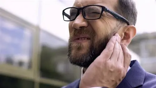 Молодой человек страдает от боли в ухе