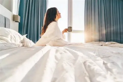 Женщина сидит на кровати с утренним кофе