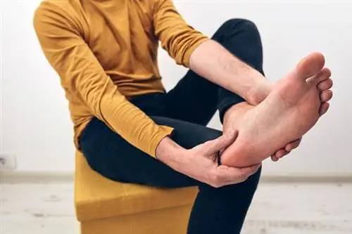 Мужчина держит ногу