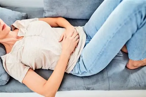 Женщина держится за живот из-за болей в животе.