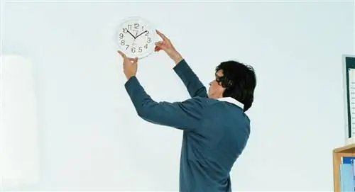 мужчина настраивает часы в офисе