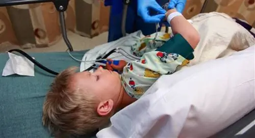 Средняя часть доктора, осматривающего мальчика, лежащего на кровати