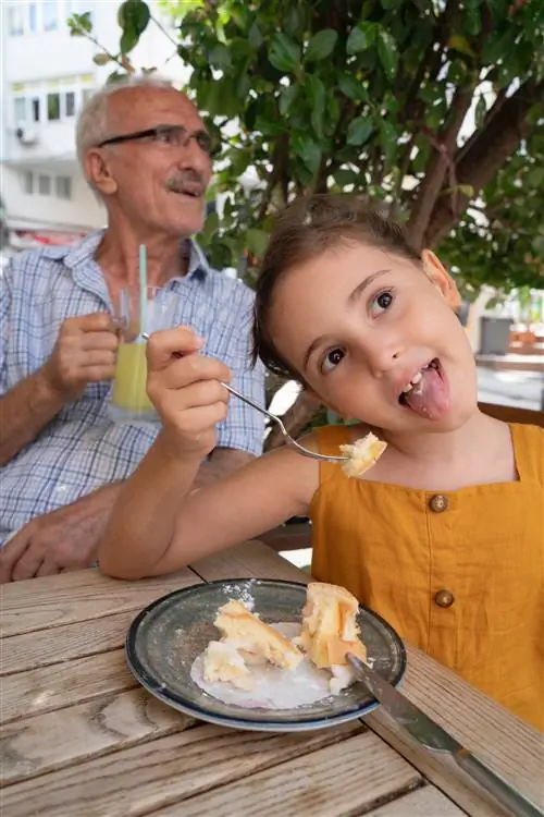 Дедушка и внучка вместе едят торт в кафе