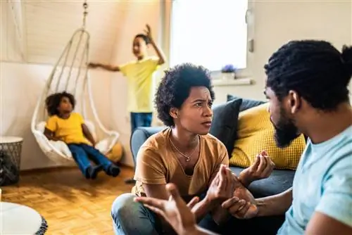 Обеспокоенные афроамериканские родители спорят в гостиной с детьми в гостиной.