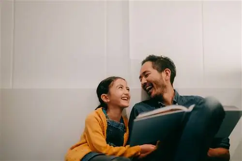 Отец и маленькая дочь читают книгу вместе дома