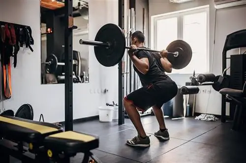 Один мужчина, подтянутый молодой мужчина, тренирующийся с весами в тренажерном зале.