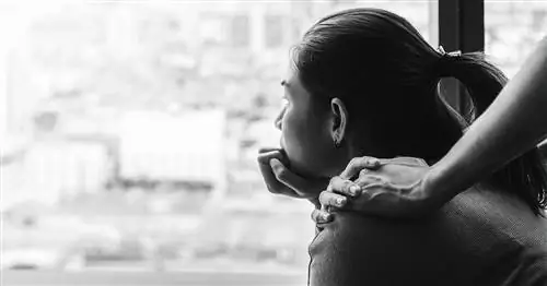 Женщина в черно-белом платье смотрит в окно, положив руку ей на плечо.