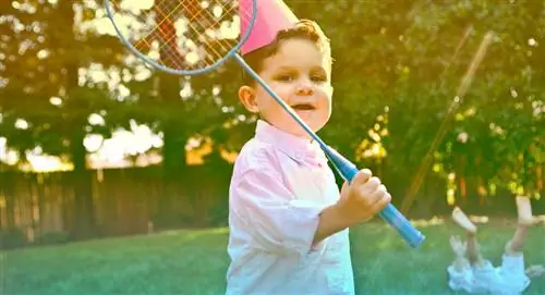 3-летний ребенок играет в бадминтон на улице на дне рождения.