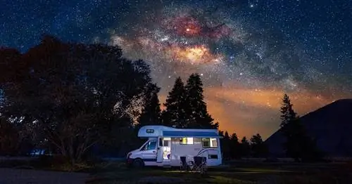 Фотография трейлера, припаркованного возле дикой природы ночью, пример альтернативы кемпинга, похожей на airbnb.