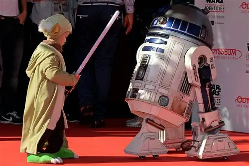КЕЛЬН, ГЕРМАНИЯ - 20 мая: Маленький мальчик, одетый как Великий Магистр Йода, встречает модель R2-D2 на р…
