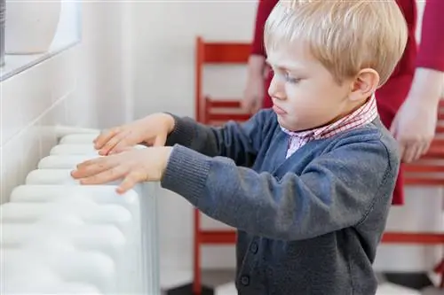 Ребенок трогает радиатор, хмурится.