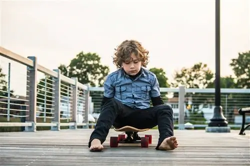 Неуверенный в себе ребенок сидит на скейтборде.