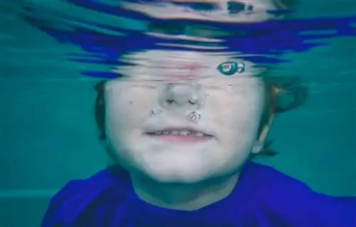 Молодой мальчик окунул голову под воду.