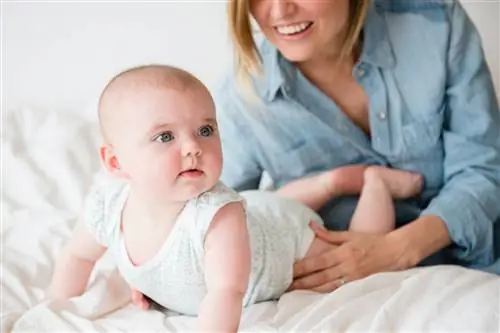 Мама помогает ребенку проводить время на животике.