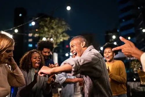 Счастливые друзья танцуют во время вечеринки ночью