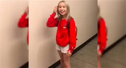 Звезда Instagram Лил Тэй стоит в красном свитере и белых шортах, убирая волосы от него…