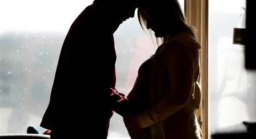 силуэт мужчины, кладущего руку на живот беременной жены