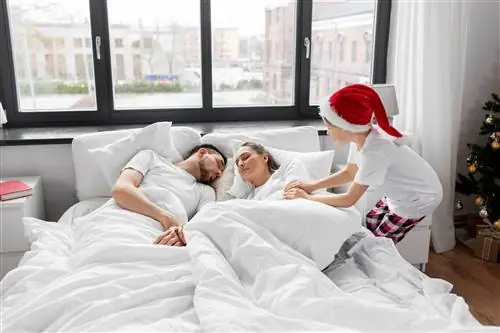 семья, зимние каникулы и концепция людей - счастливый маленький сын будит своих мать и отца в рождестве…