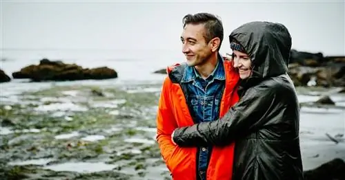 Мужчина и женщина обнимаются на дождливом пляже