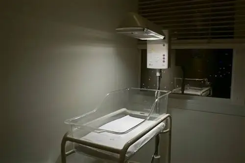 согревающая люлька стоит пустой в темном углу больничной палаты