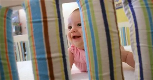 ребенок находится в кроватке с бампером для кроватки