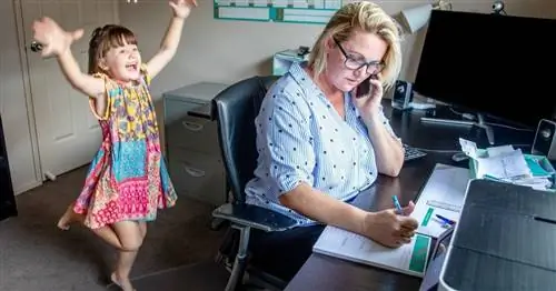 девочка играет за мамой, которая работает дома за своим столом