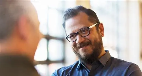 Мужчина в очках и с бородой слушает, как кто-то говорит