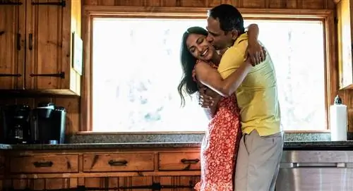 Счастливые муж и жена обнимаются на кухне.