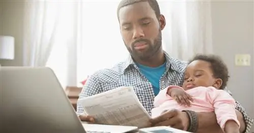 папа смотрит на купюру со спящим младенцем на руках