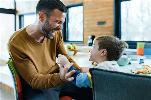 Веселый отец и его маленький мальчик веселятся дома.