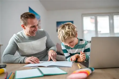 Снимок талии гордого одинокого белого отца, указывающего на ответы в блокноте маленькому сыну. Они есть …