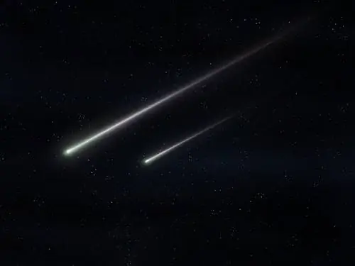 Два метеорита летят в ночном небе. Яркие метеоры светятся в атмосфере. Красивые падающие звезды…