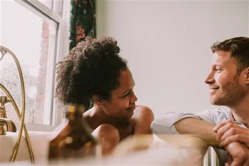 Женщина в ванне смотрит на своего партнера, который снова отдыхает в ванне