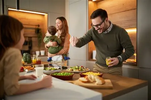 Счастливый отец заканчивает перекусить для своей семьи на кухне.