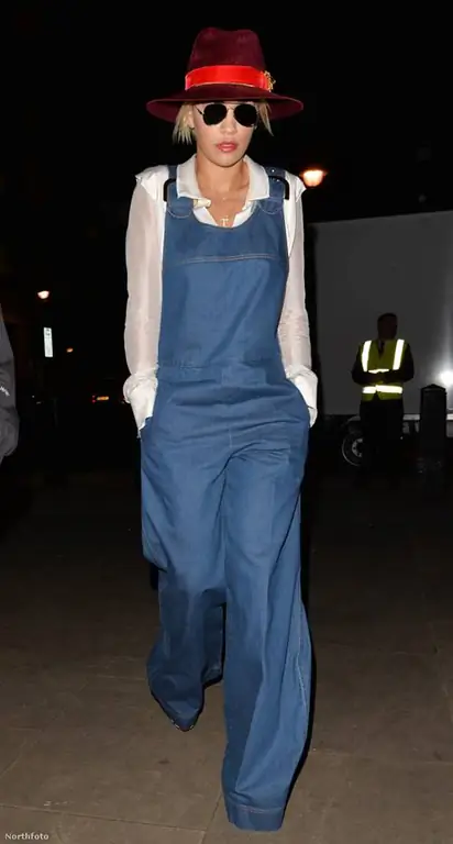 Рита Ора сочетала свой мешковатый комбинезон с прозрачной белой блузкой и шляпой, перевязанной красной лентой