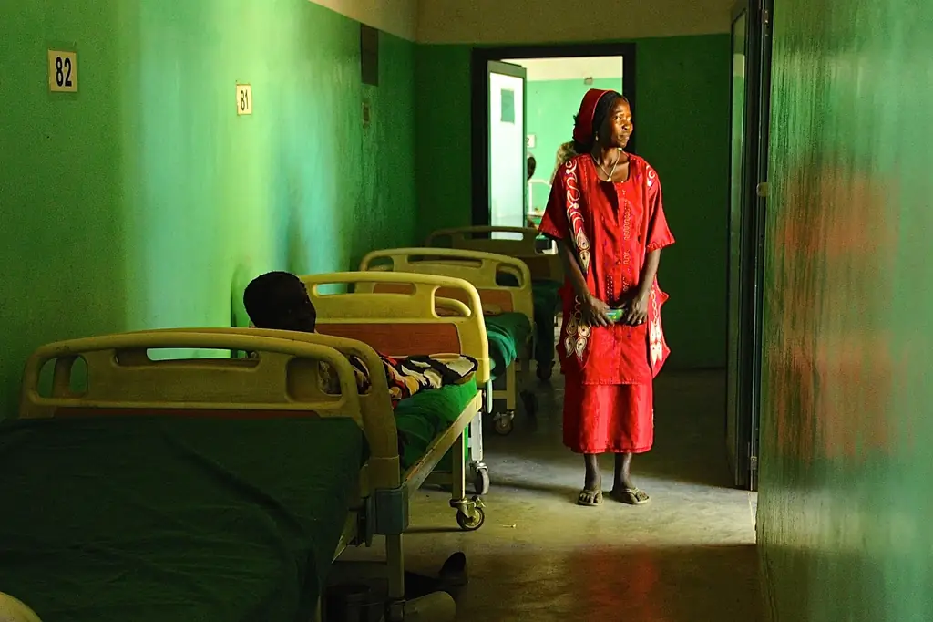 Мать стоит у кровати своего ребенка в больнице Матери Милосердия