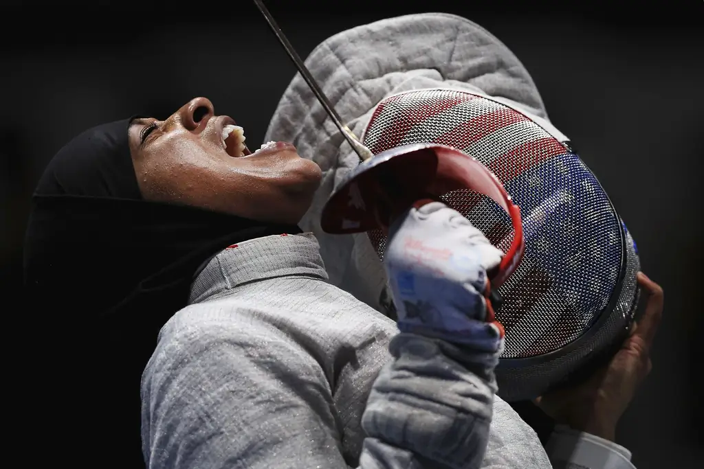 РИО-ДЕ-ЖАНЕЙРО, БРАЗИЛИЯ - 13 августа: Ибтихай Мухаммед из США реагирует на Софью Великую из России во время полуфинала 1 женской сборной по сабле Россия против США на арене Кариока 3 13 августа 2016 года в Рио-де-Жанейро, Бразилия. (Фото Тома Пеннингтона/Getty Images)