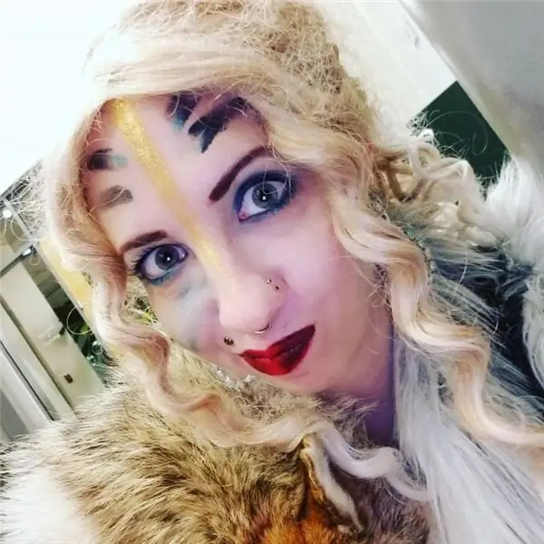 женщина с вьющимися светлыми волосами, раскрашенным лицом, красными губами и мехами