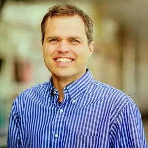 Мужчина в полосатой рубашке на фоне не в фокусе